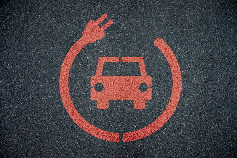 Red EV charging sign painted on asphalt
