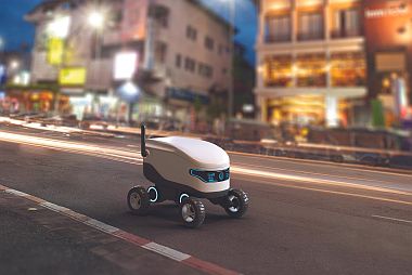 a small service robot down a city street at night
