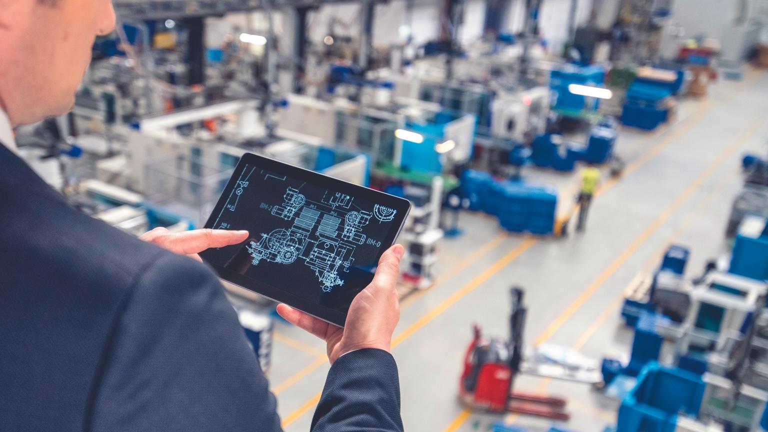 Man using a tablet device to oversee a manufacturing automation in a factory