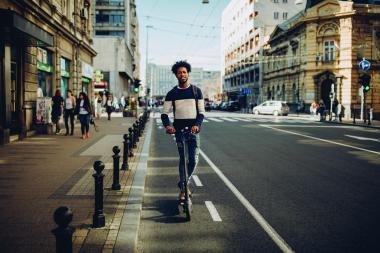 Person riding an electric scooter in a city street representing GNSS positioning for micromobility applications
