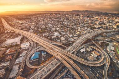 Aerial view of urban highway interchange at sunset, illustrating the need for high-precision RTK GNSS positioning in connected vehicles and autonomous systems