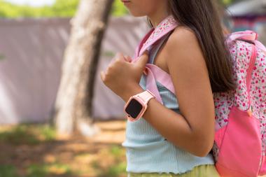 Child wearing a smartwatch and backpack, illustrating a wearable device for location tracking and safety