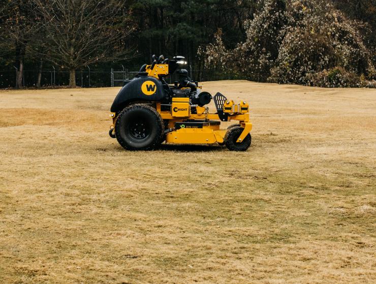a yellow and black mower sitting on top of a dry grass field a yellow and black mower sitting on top of a dry grass field