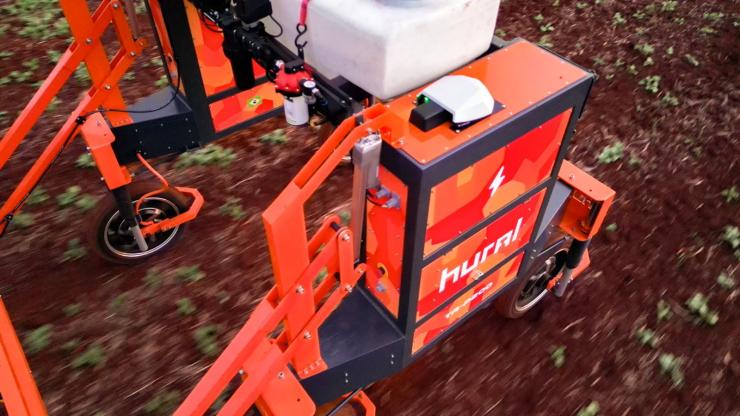 Close up view of the Hural agricultural robot operating between crop rows in a cultivated field. Precision positioning equipment is mounted on the autonomous farming platform to support accurate navigation during field operations.