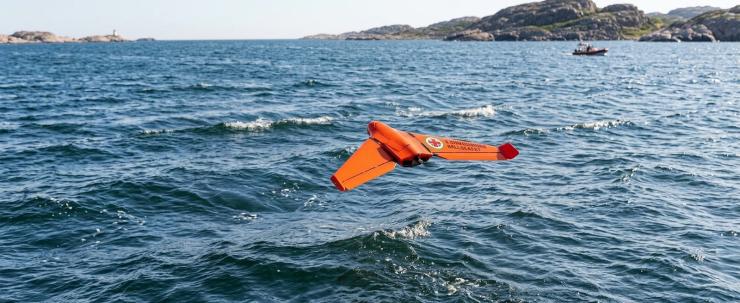A fixed wing UAV flies above open water during maritime search and rescue operations while testing autonomous drone navigation and recovery technologies