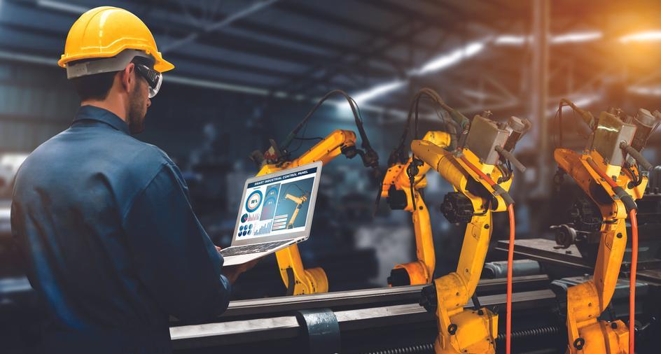 person in automated factory is controlling parameters in laptop