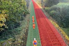 A bird's eye view of railway construction workers wearing high-visibility jackets walking next to an open rail track