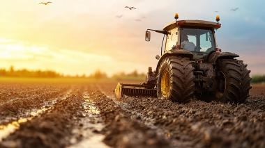 An autonomous farming machine navigates a muddy rice field at sunset, demonstrating precision agriculture practices. Accurate positioning technologies such as GNSS help enable efficient agricultural automation and field operations.