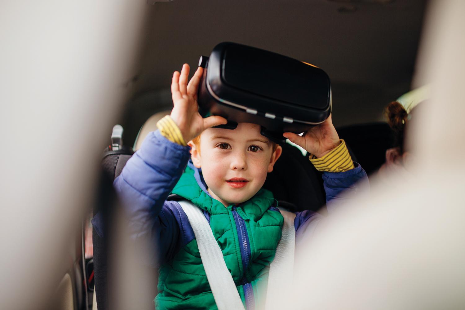 Kid using Virtual Reality goggles in the back seat