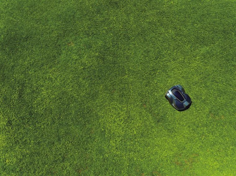 Aerial view of an autonomous robotic lawn mower operating on a green lawn